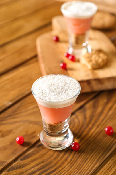 Shot of delicious pudding with coconut shavings and cranberry on wooden table - Fotografie, Obrázek