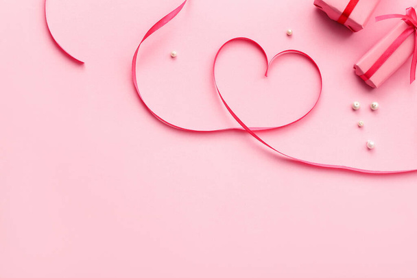 Серце зроблене з стрічки, намиста і подарунків на рожевому фоні. День святого Валентина. - Фото, зображення