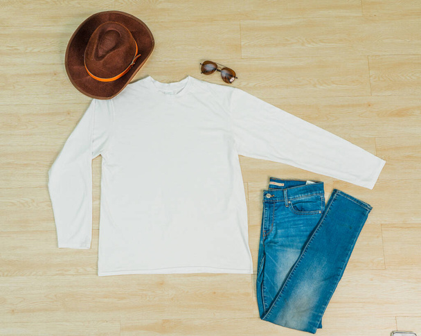 A shirt laid out on the top of the wooden tiling, with a hat and a jeans near it, minimalist decoration - Photo, Image