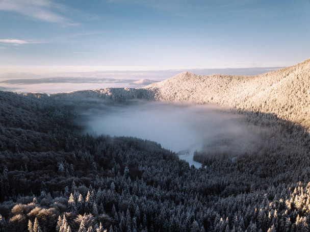 Gün doğumunda kış boyunca karlı dağ gölü üzerinde sabah bulutları. Saint Anne Gölü, Romanya 'dan gelen tek volkanik göl.. - Fotoğraf, Görsel