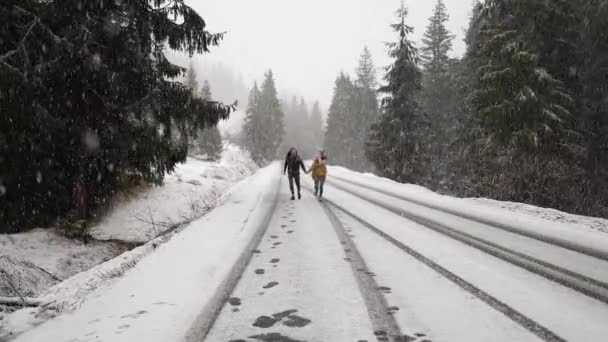 Young multiethnic couple in warm sweaters date in winter forest at Christmas vacation. Happy cheerful man and woman enjoy first snow at New Year holidays. Outdoor activity, cold weather. Christmas eve - Filmati, video