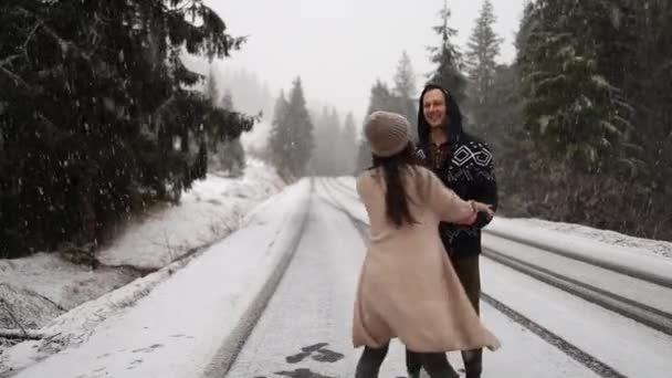 Young multiethnic couple in warm sweaters date in winter forest at Christmas vacation. Happy cheerful man and woman enjoy first snow at New Year holidays. Outdoor activity, cold weather. Christmas eve - Imágenes, Vídeo