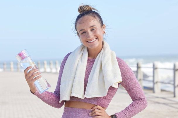 Face, beach and woman with water bottle for drinking water after running, workout or exercise training. Sports, portrait and female from Canada with liquid for hydration streaming music on earphones - Foto, immagini