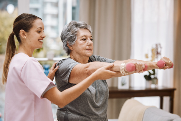 Women, senior or physiotherapy help with dumbbell in wellness clinic, healthcare center or nursing home living room. Smile, happy or physiotherapist nurse and elderly patient in weight rehabilitation. - Foto, immagini