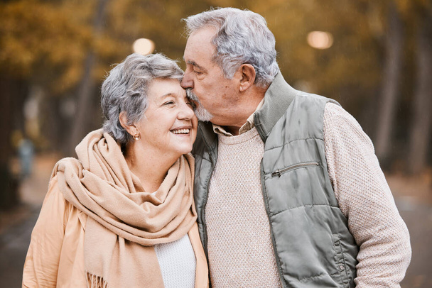 Love, kiss and senior couple in park enjoying weekend, quality time and romantic bonding together. Retirement, relationship and elderly man and woman walking, hugging and embrace outdoors in nature. - Foto, Imagen