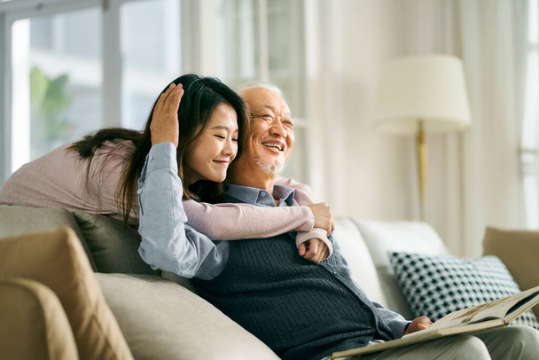Asyalı yetişkin kız ve kıdemli baba sohbetin tadını çıkarıyor ve evde iyi vakit geçiriyor. - Fotoğraf, Görsel