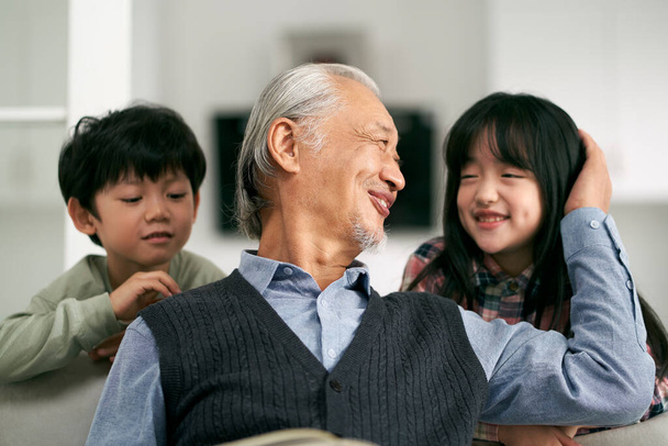 senior asian grandfather having a good time with two grandchildren at home - Photo, image