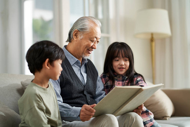 senior asian grandfather having a good time with two grandchildren at home - Photo, Image