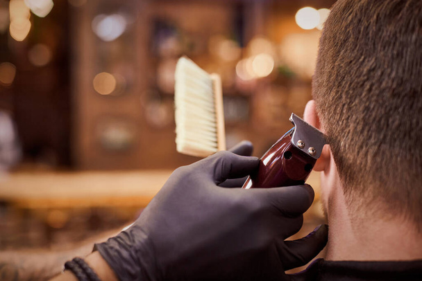 Male haircut trimming in barbershop, client getting haircut by hairdresser with clipper and hairbrush. Hairdresser makes hairdo in hairdresser salon, new stylish modern haircut for man - Photo, Image