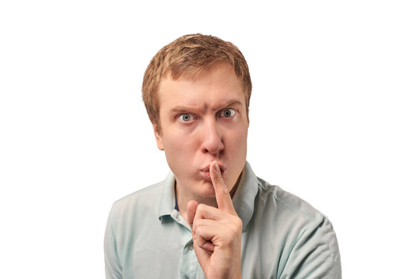 Funny guy in light gray Polo T-shirt asking to be quiet, silence gesture isolated on white background. Young man saying Shhh, keep quiet, please and making silence gesture, request for silence - Foto, immagini