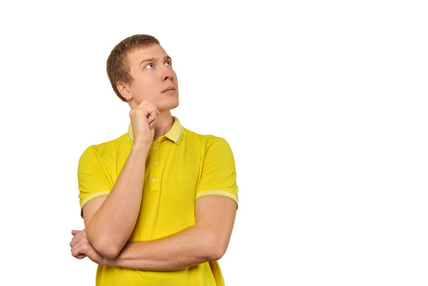 Thoughtful man in yellow T-shirt looking to right isolated on white background. Pensive young man thinking, guy putting hand to his head and looking to right, philosophical reflection concept - Fotoğraf, Görsel