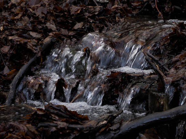 Kaunis pieni virtaava joki, joka johtuu lumen sulamisesta ja muodostaa puhtaan kaskadin makealla viileällä vedellä, jota ympäröi kasvillisuus luonnonkivisellä vuorella. - Valokuva, kuva