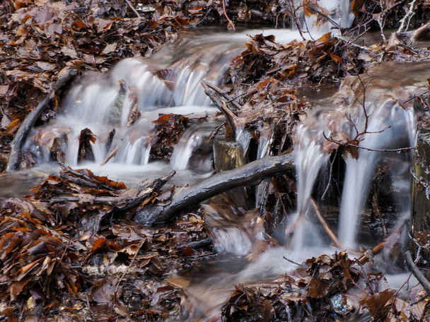 Kaunis pieni virtaava joki, joka johtuu lumen sulamisesta ja muodostaa puhtaan kaskadin makealla viileällä vedellä, jota ympäröi kasvillisuus luonnonkivisellä vuorella. - Valokuva, kuva