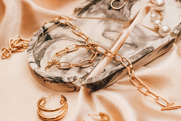 Женские украшения, золотая цепь, модные украшения на шелковом фоне. - Фото, изображение