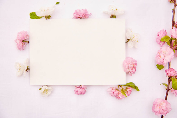 Delicate briefpapier kaart mockup met lente wit en roze bloemen. Romantisch, bruiloft, verjaardag, uitnodiging, Moederdag modelleert het kaartconcept. Begrepen, ruimte. Uitzicht van bovenaf. - Foto, afbeelding