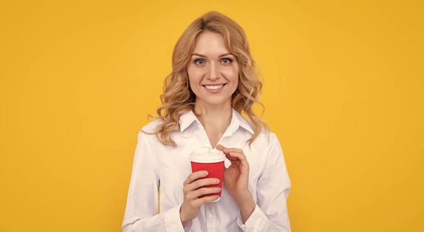 glimlachende blonde vrouw met koffie kopje op gele achtergrond. - Foto, afbeelding