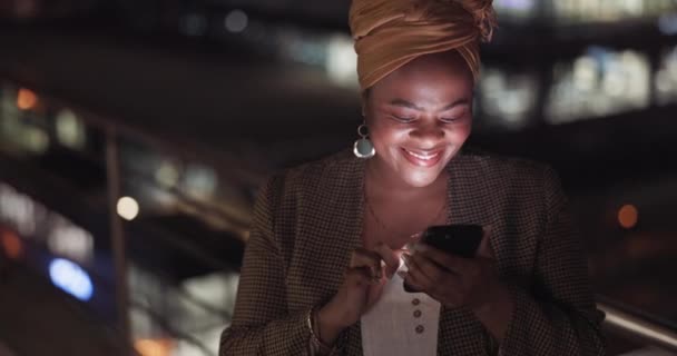 City, rooftop and black woman on a phone at night networking on social media or the internet. Technology, happiness and African lady browsing online with a cellphone on an outdoor balcony in a town - Filmati, video