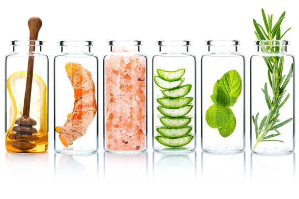 The glass bottle of homemade skin care and body scrubs with natural ingredients aloe vera ,himalayan salt ,peppermint ,rosemary ,turmeric and honey isolate on white background. - Foto, imagen