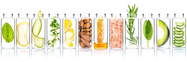 Homemade skin care with natural ingredients avocado ,aloe vera ,cucumber ,himalayan salt  ,honeycomb ,almonds, ginger slice and rosemary  in glass bottles isolate on white background. - Foto, imagen