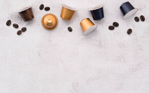 Dark roasted coffee beans and coffee capsule setup on white concrete background with copy space. - Foto, Imagen
