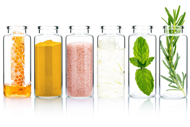 The glass bottle of homemade skin care and body scrubs with natural ingredients aloe vera ,himalayan salt ,peppermint ,rosemary ,turmeric and honey isolate on white background. - Foto, Imagem