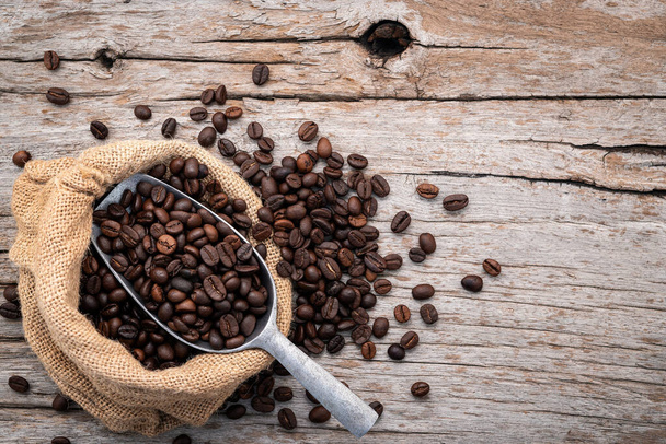 Background of dark roasted coffee beans with scoops setup on wooden background with copy space. - Fotografie, Obrázek