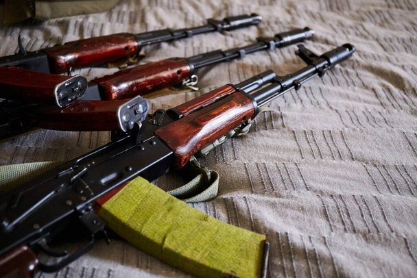 Kalashnikov assault rifle on bed. Ukrainian home. Russia's military aggression against Ukraine - Foto, immagini