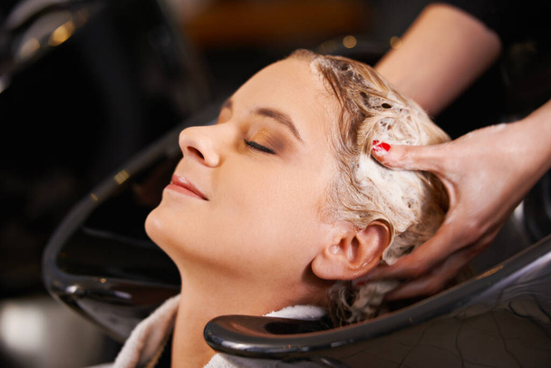 Massaging in the condtioner. a young woman having her hair washed at a hair salon - Photo, image