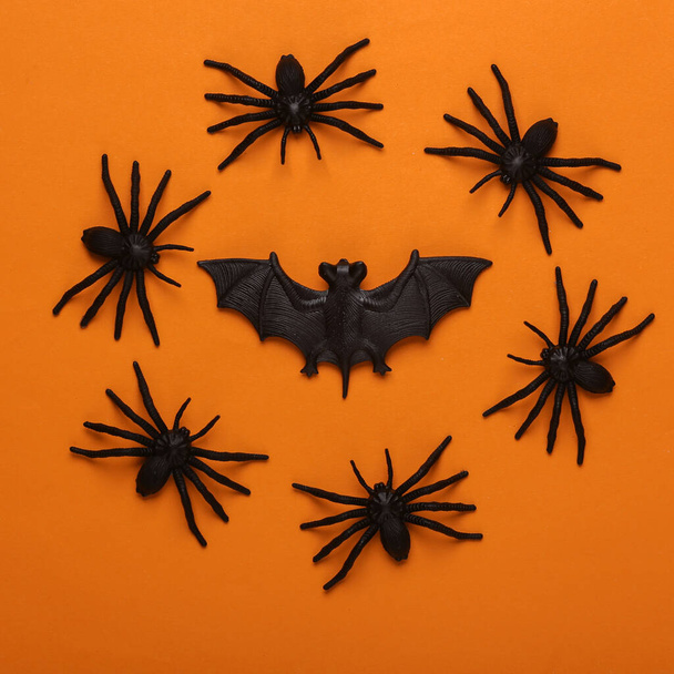 Aranhas de plástico com morcego no fundo laranja. Decoração de Halloween. Vista superior - Foto, Imagem