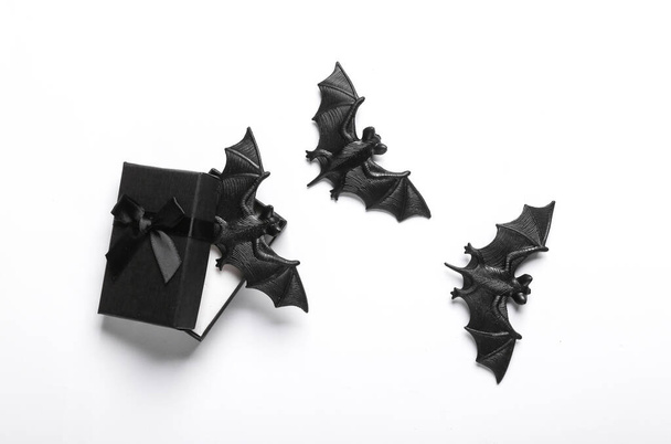 Schwarze Geschenkschachtel mit Fledermäusen auf weißem Hintergrund. Kreatives Halloween-Layout. Ansicht von oben. Flache Lage - Foto, Bild