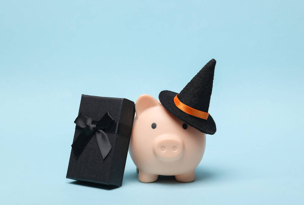 Halloween malac bank boszorkány kalap és ajándék doboz kék háttér - Fotó, kép