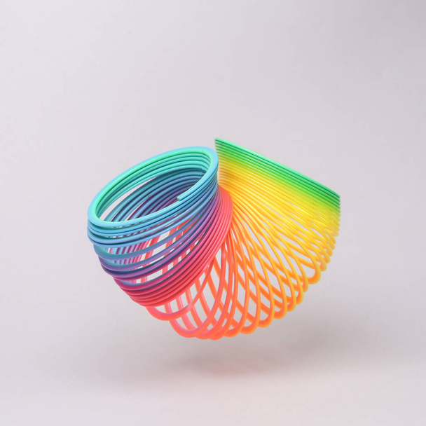 Rainbow spiral toy flying in antigravity on gray background with shadow. Levitation object in the air. Creative minimal layout - Foto, Imagem