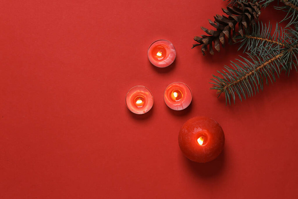 Red flaming aroma candles with a Christmas tree branch. Christmas mystery. Aromatherapy, beauty, spa. Red background. Top view - Photo, image