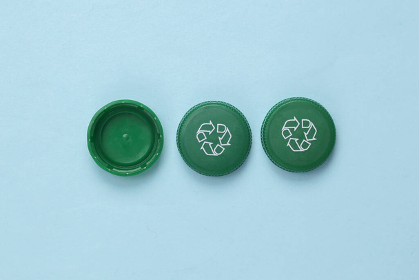 Plastic bottle caps with recycle symbol on blue background. Eco concept - Foto, Imagem