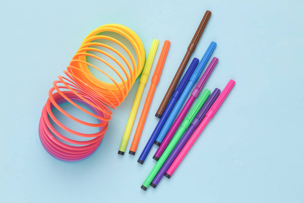 Autism, child development. Antistress rainbow spiral toy with felt-tip pens on a blue background - Foto, Imagem