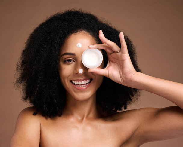 Portrait, container and beauty with a model black woman in studio on a brown background for skin treatment. Face, product and skincare with an attractive young female posing to promote antiaging care. - Foto, Imagen