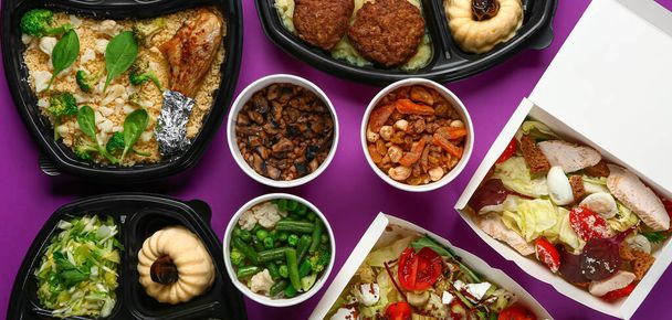 Containers with delicious food for delivery on purple background - Photo, image