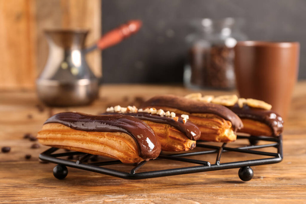 Grid with tasty chocolate eclairs on wooden table - Foto, Bild