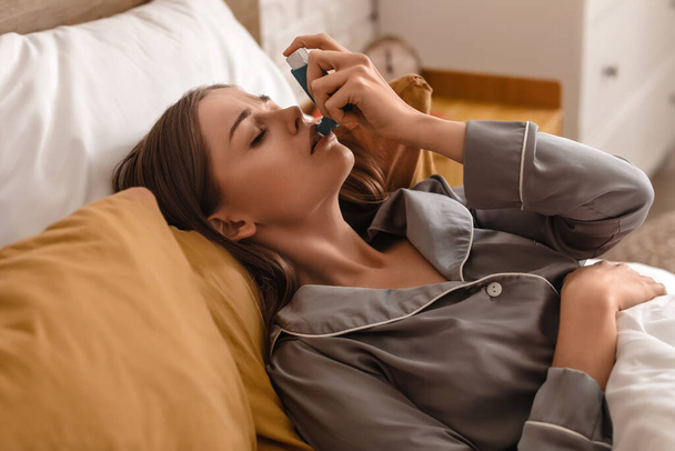 Sick young woman with inhaler in bed - Photo, Image