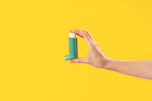 Hand of young woman with inhaler on yellow background - Foto, Bild