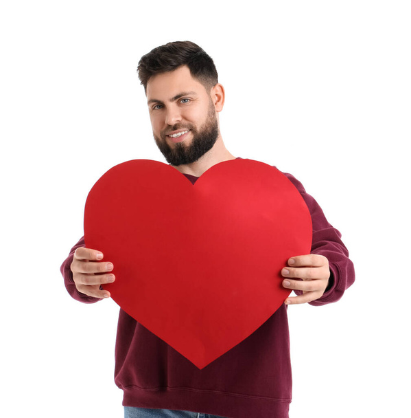 Young bearded man with big paper heart for Valentine's Day on white background - Foto, Bild