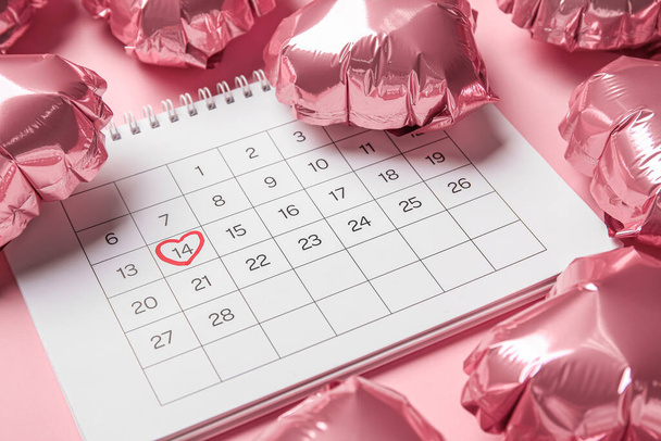 Calendar with marked date of Valentine's Day and balloons on pink background, closeup - Foto, Imagem