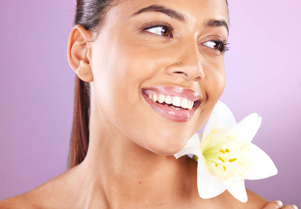 Beauty, wellness and woman with a lily flower in studio for a health, cosmetic and natural face routine. Skincare, health and healthy girl model from Brazil with floral isolated by purple background - Photo, image