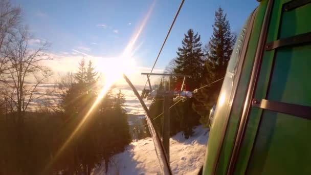 CLOSE UP: Beautiful descent from ski resort with cable car after snowboarding. Picturesque ride with cable car from mountain down to misty valley after winter sports activities at alpine ski area. - Filmagem, Vídeo