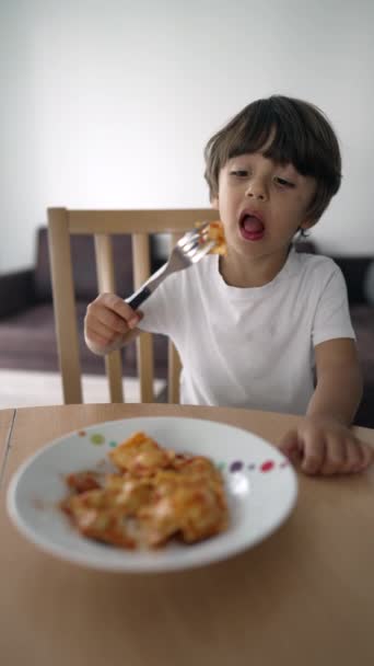 Kleine jongen die pasta eet op het bord. Kind eet de lunch alleen. Koolhydraten in verticale video - Video