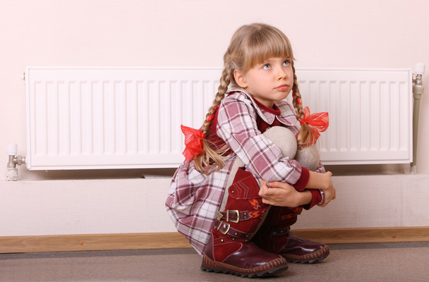 Chica triste sentada cerca del calentador. Problema de niños
. - Foto, Imagen
