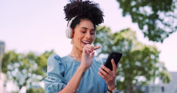 Music, phone and headphones, woman in park happy and excited while dancing in garden trees. Technology, smartphone and dance, happy woman enjoying streaming service or free internet radio station - Footage, Video