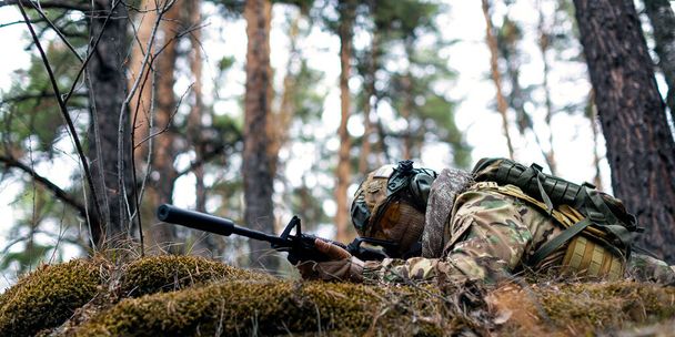 A professional special forces fighter during a special operation - he aims at the enemy. A clash or ambush in the forest. The concept of modern military operations and a special operation on enemy - Foto, Imagen