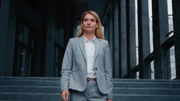 Young successful business woman goes down stairs and walks near office building confident motivated proud businesswoman leader director boss entrepreneur finishes work day walking downtown outdoors - Filmati, video