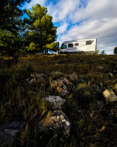 Modern camper van motor home parked in the free nature alone. Mountains countryside travel concept with vehicle. Vanlife. Alternative transport for holiday vacation. Vertical image. Road trip - Photo, image